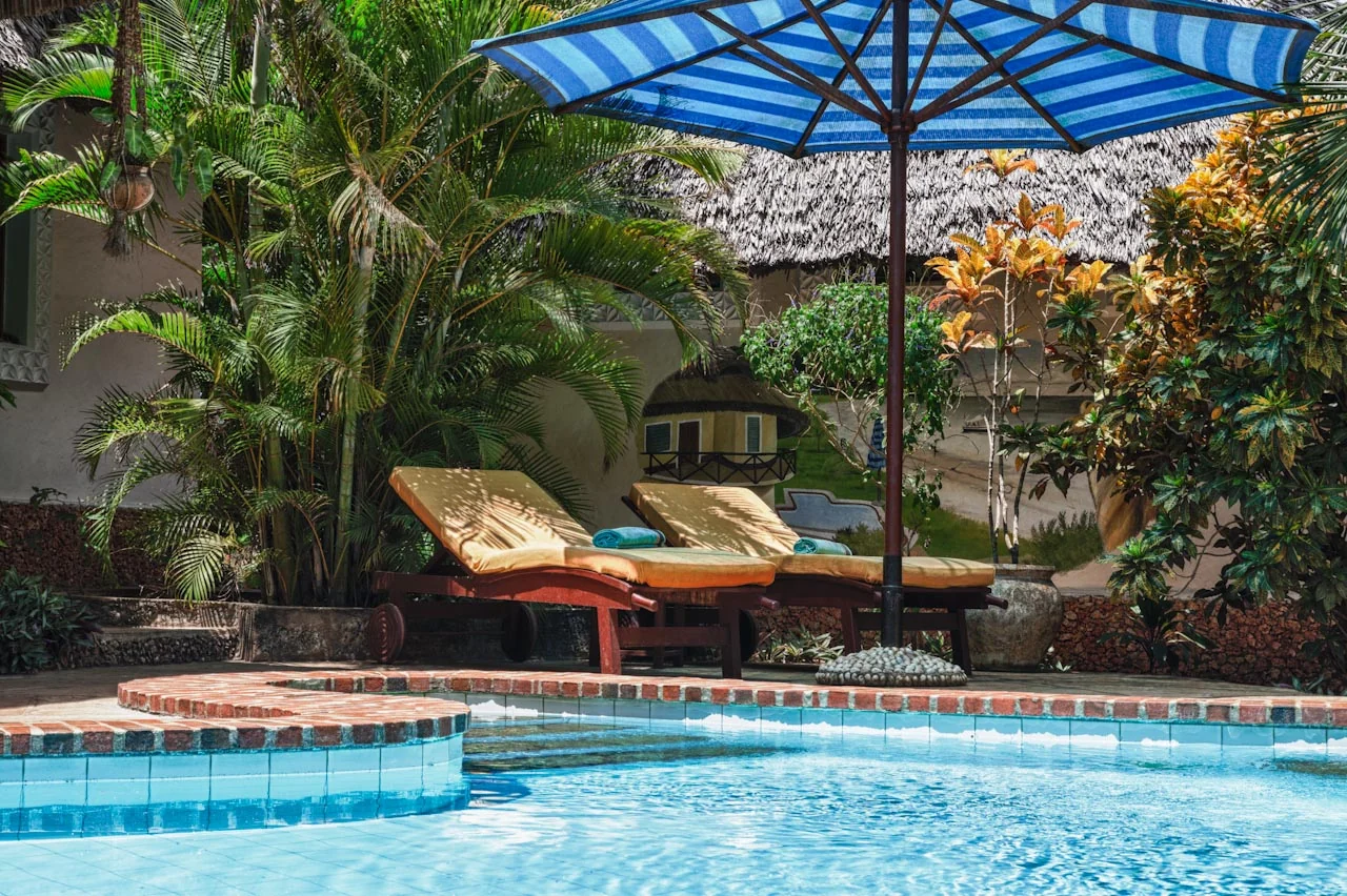 Sun loungers under a striped umbrella beside the pool